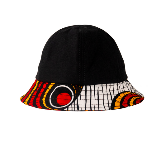 A bucket hat with a solid black crown and a wide brim featuring a vibrant African wax print pattern in red, yellow, black, and white.