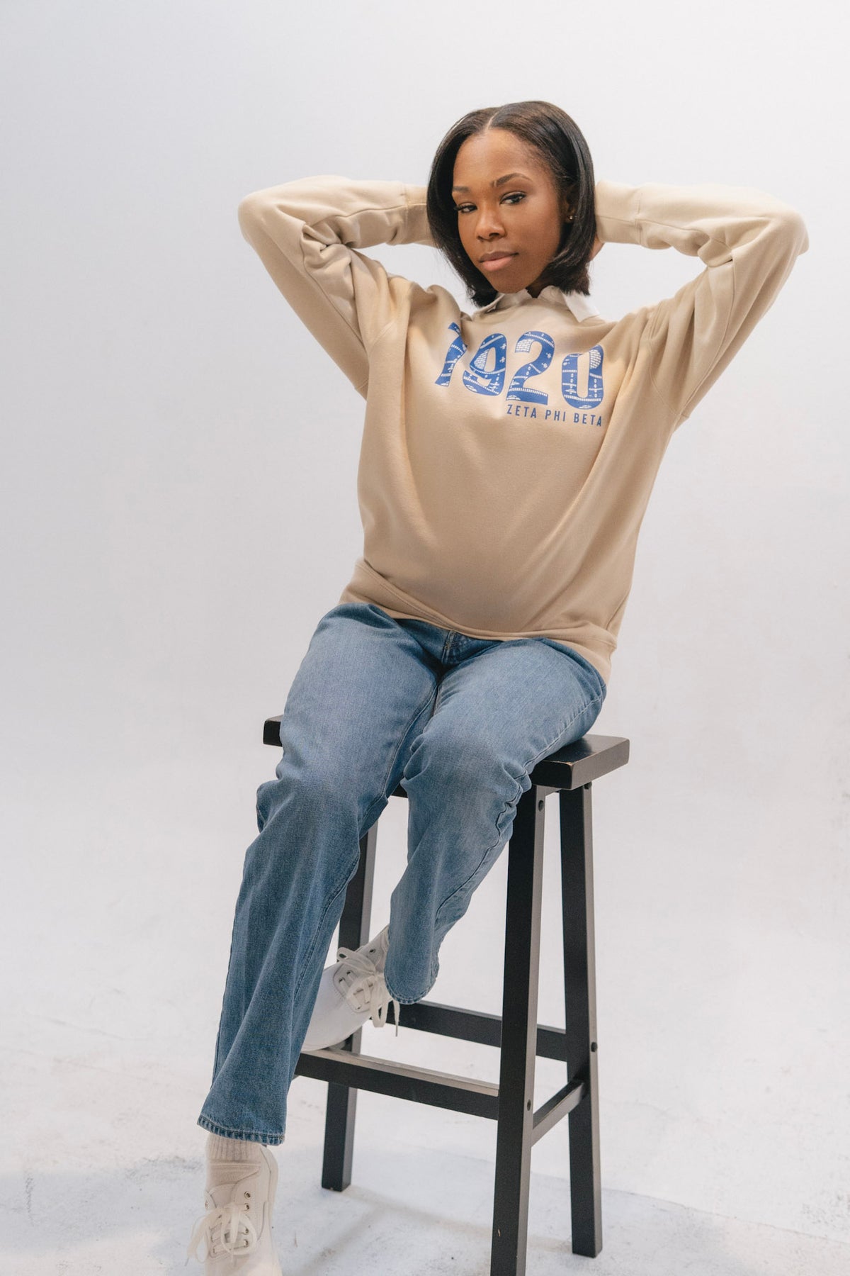 Model wearing dust Zeta Phi Beta 1920 sweatshirt in a white studio